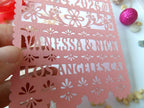 Rose color save the date with cut-out designs and text held by a hand.